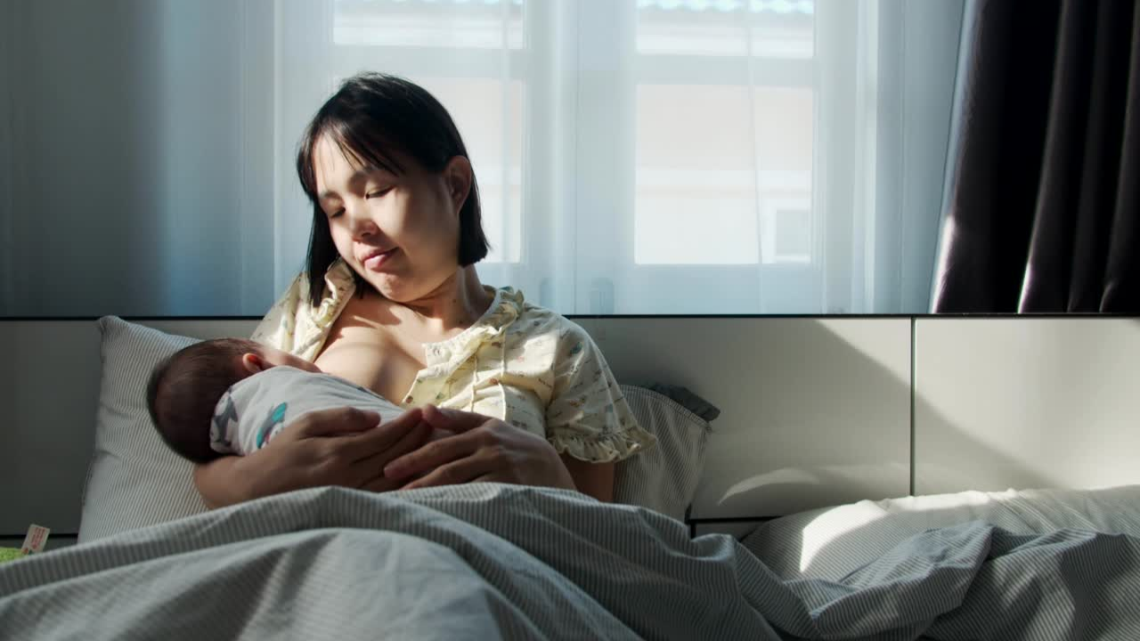 Woman breastfeeds her baby in bed after her home birth.